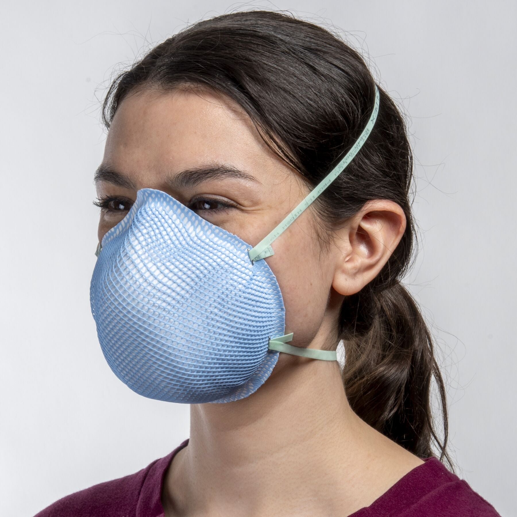 Woman healthcare worker wearing low profile nose bridge blue health care NIOSH N95 surgical respirator from Canada Strong Masks.